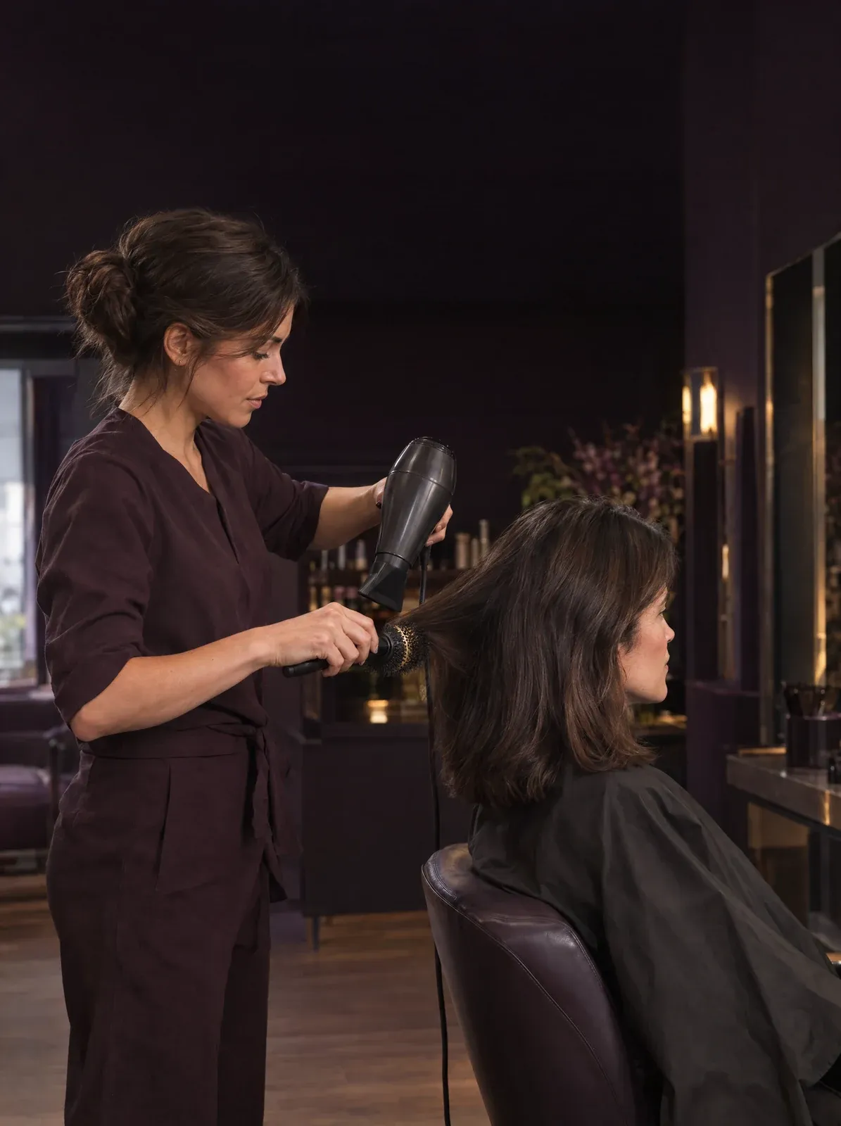 Coiffeuse qui réalise un brushing à une cliente dans son salon de coiffure
